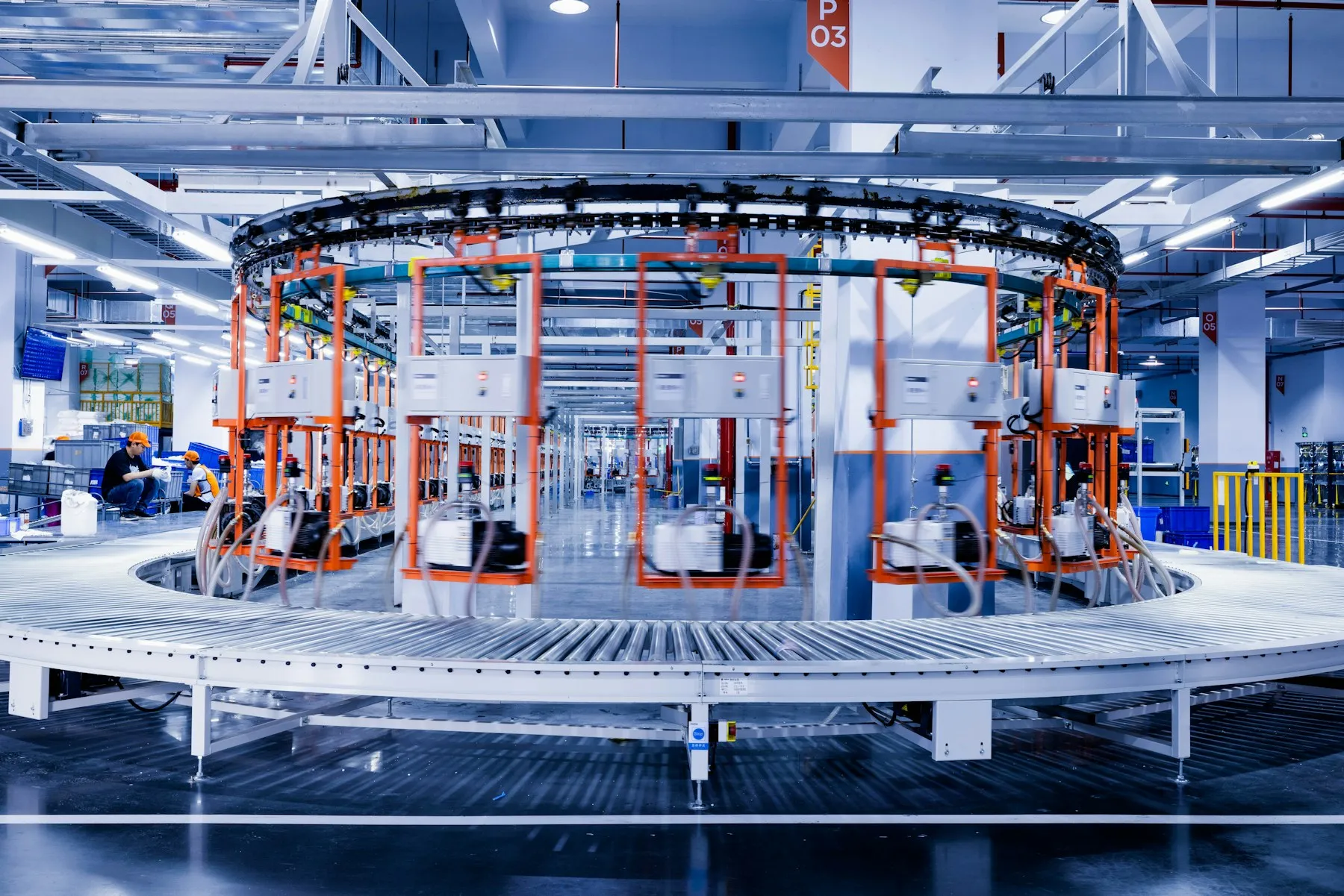 Engineers working beside a circular conveyor system on a plant floor